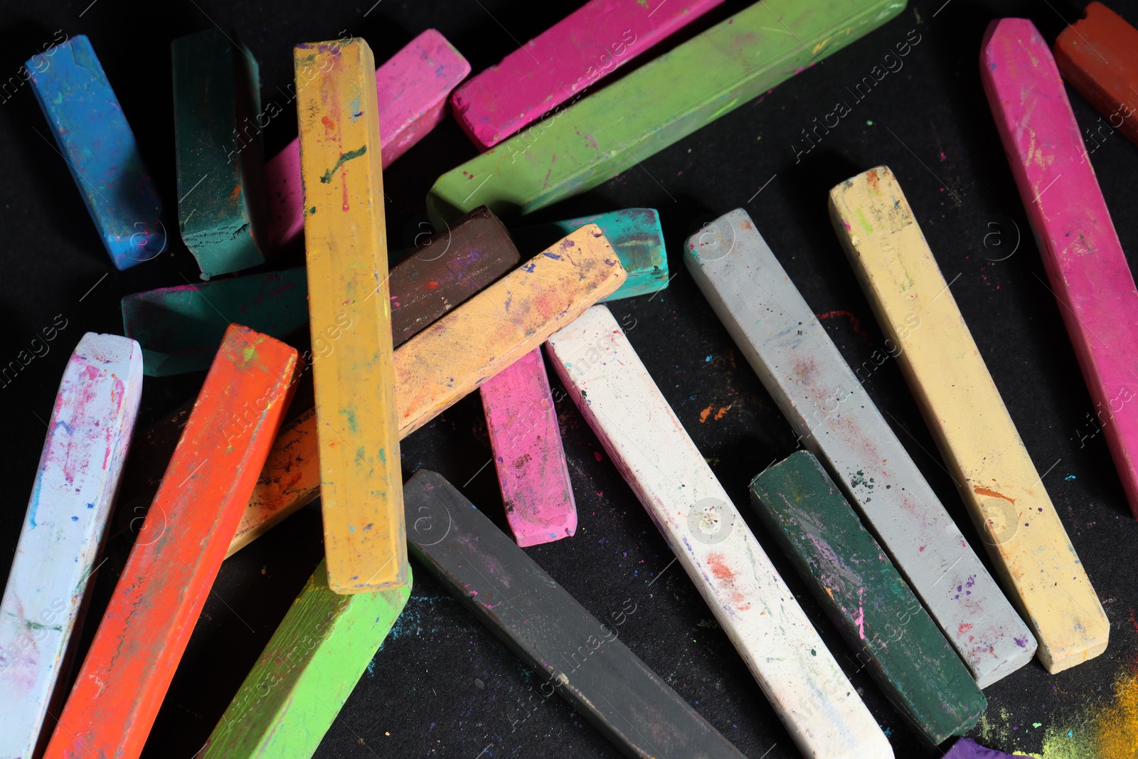 Colorful chalk pastels on black background, above view Photo of Colorful chalk pastels on black background, above view