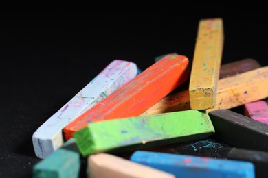 Photo of Colorful chalk pastels on black background, closeup