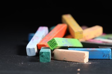 Photo of Colorful chalk pastels on black background, closeup