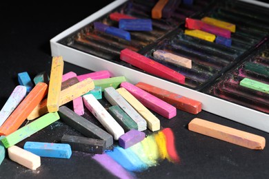 Photo of Set of colorful chalk pastels on black background, closeup