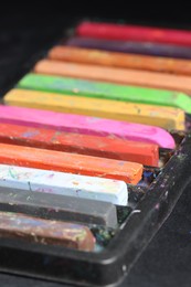 Photo of Set of colorful chalk pastels on black background, closeup