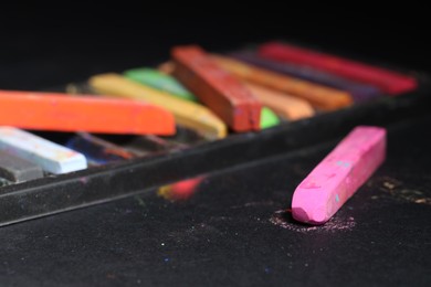 Photo of Colorful chalk pastels on black background, closeup