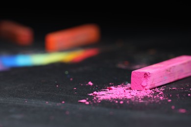 Photo of Pink chalk pastel on black table, closeup