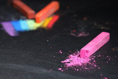 Photo of Pink chalk pastel on black table, closeup