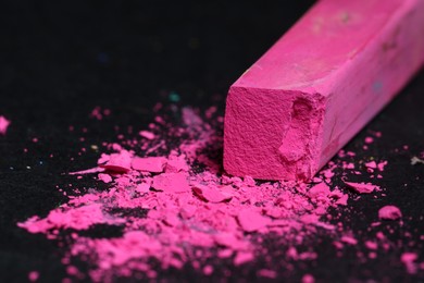 Photo of Pink chalk pastel on black table, closeup. Space for text