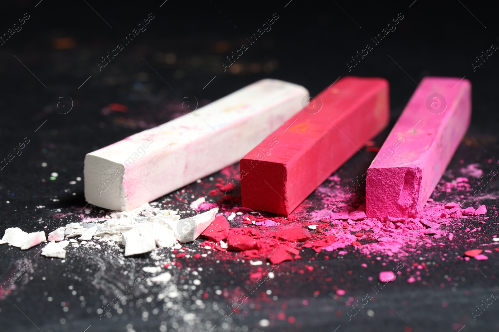 Photo of Colorful chalk pastels on black background, closeup