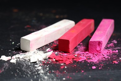 Photo of Colorful chalk pastels on black background, closeup
