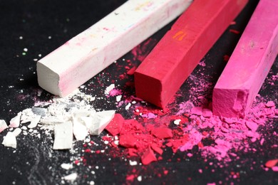 Photo of Colorful chalk pastels on black background, closeup