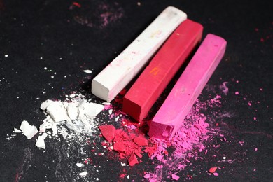 Photo of Colorful chalk pastels on black background, closeup