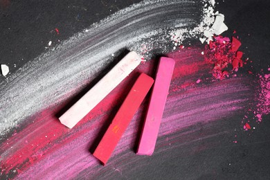 Photo of Colorful chalk pastels on black background, flat lay