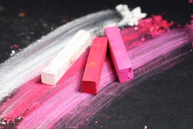Photo of Colorful chalk pastels on black background, closeup