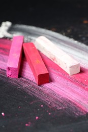 Photo of Colorful chalk pastels on black background, closeup