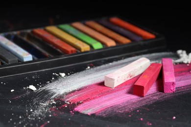 Photo of Many colorful chalk pastels on black background