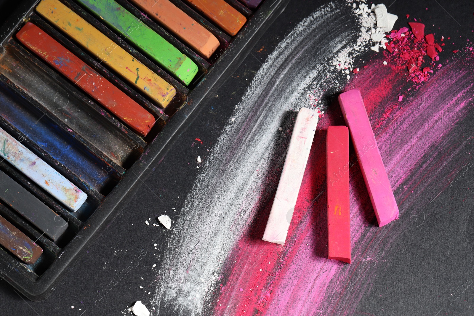 Colorful chalk pastels on black background, flat lay Photo of Colorful chalk pastels on black background, flat lay