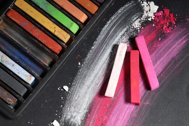 Photo of Colorful chalk pastels on black background, flat lay
