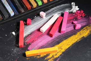 Photo of Many colorful chalk pastels on black background