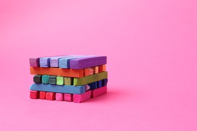 Photo of Many colorful chalk pastels on pink background. Space for text