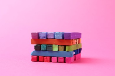 Photo of Many colorful chalk pastels on pink background