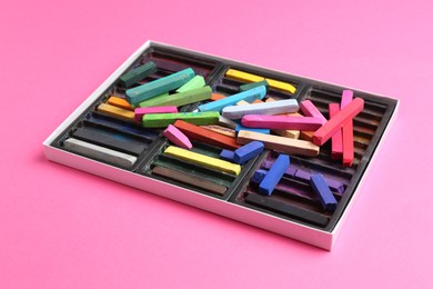 Photo of Set of colorful chalk pastels on pink background