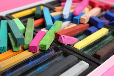 Photo of Set of colorful chalk pastels on pink background, closeup