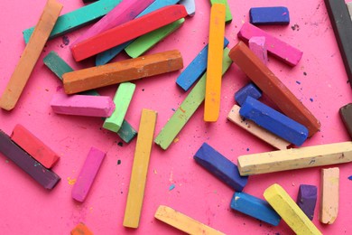 Photo of Many colorful chalk pastels on pink background, flat lay