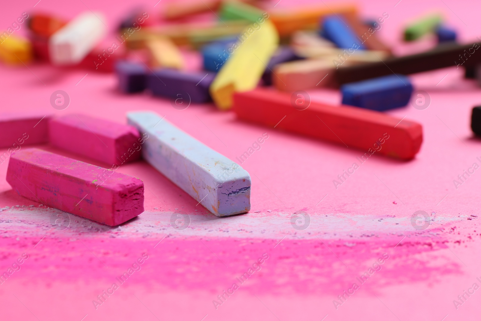 Many colorful chalk pastels on pink background, closeup Photo of Many colorful chalk pastels on pink background, closeup