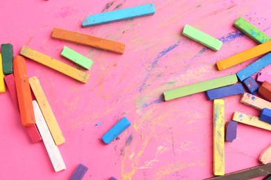 Photo of Many colorful chalk pastels on pink background, flat lay