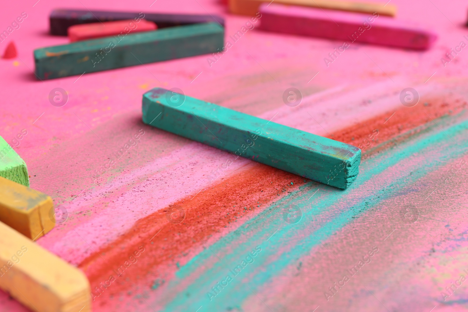 Many colorful chalk pastels on pink background, closeup Photo of Many colorful chalk pastels on pink background, closeup