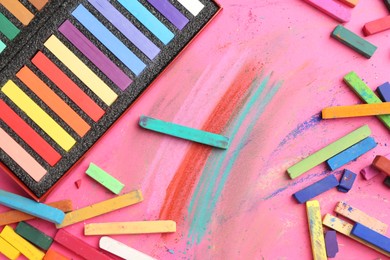 Photo of Many colorful chalk pastels on pink background, flat lay