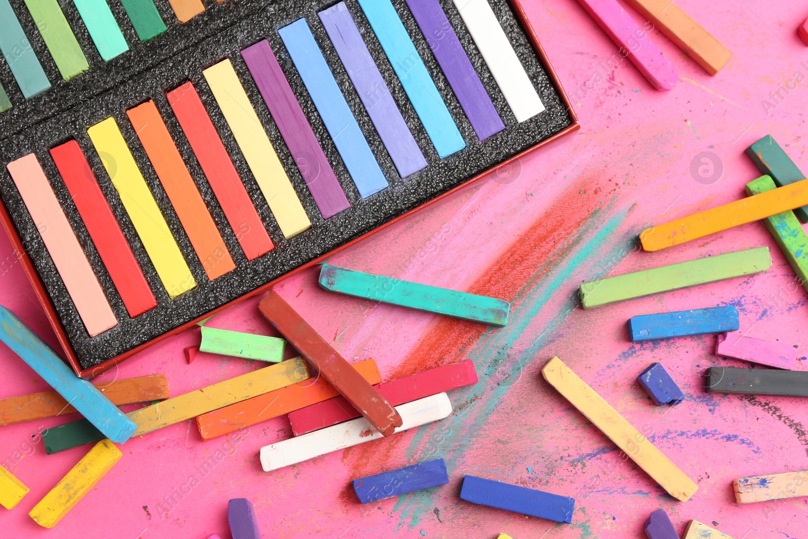 Many colorful chalk pastels on pink background, flat lay Photo of Many colorful chalk pastels on pink background, flat lay