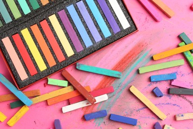 Photo of Many colorful chalk pastels on pink background, flat lay