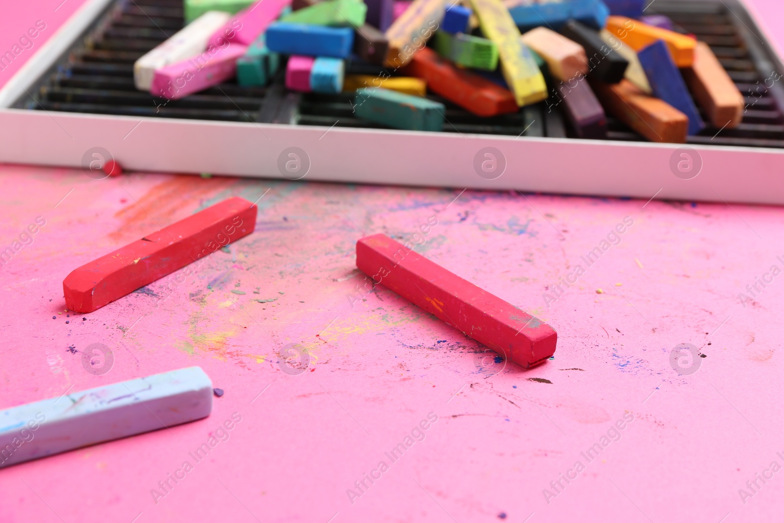 Many colorful chalk pastels on pink background, closeup Photo of Many colorful chalk pastels on pink background, closeup
