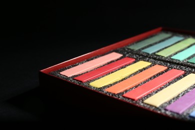 Photo of Many colorful chalk pastels on black background, closeup. Space for text