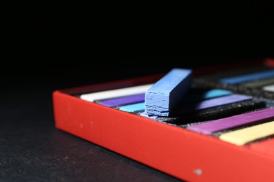 Photo of Many colorful chalk pastels on black background, closeup. Space for text