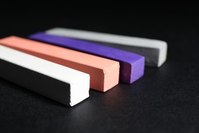 Photo of Many colorful chalk pastels on black background, closeup