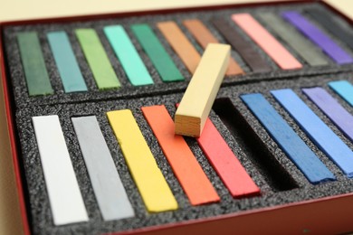 Photo of Set of colorful chalk pastels on beige background, closeup