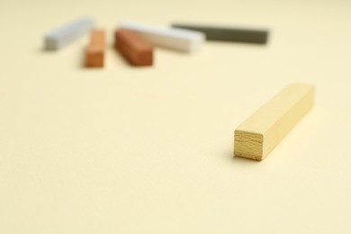 Photo of Many colorful chalk pastels on beige background, closeup. Space for text