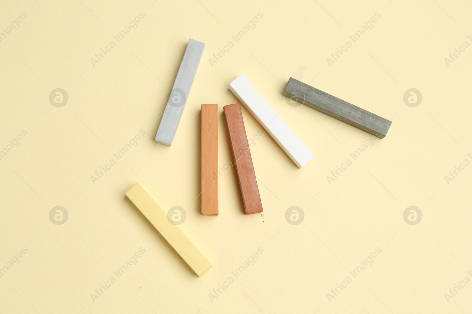 Many colorful chalk pastels on beige background, flat lay Photo of Many colorful chalk pastels on beige background, flat lay