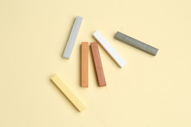 Photo of Many colorful chalk pastels on beige background, flat lay