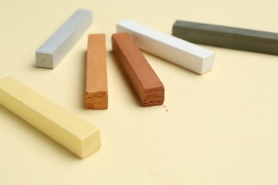 Photo of Many colorful chalk pastels on beige background, closeup