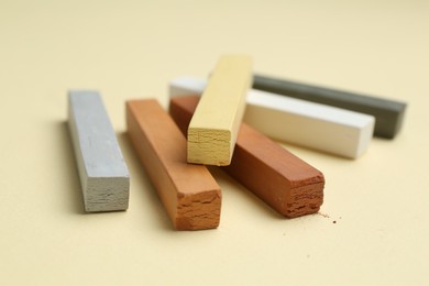 Photo of Many colorful chalk pastels on beige background, closeup