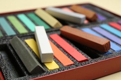 Photo of Set of colorful chalk pastels on beige background, closeup
