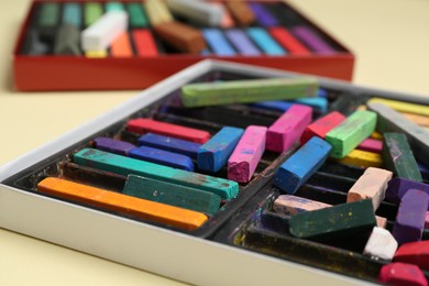 Photo of Set of colorful chalk pastels on beige background, closeup