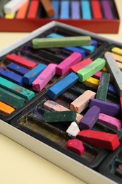 Photo of Set of colorful chalk pastels on beige background, closeup
