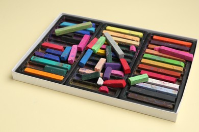 Photo of Set of colorful chalk pastels on beige background, closeup