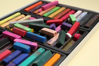Photo of Set of colorful chalk pastels on beige background, closeup