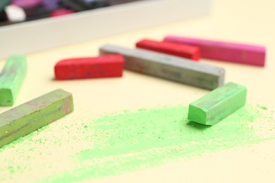 Photo of Many colorful chalk pastels on beige background, closeup