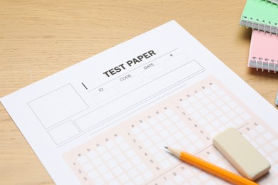 Photo of Answer sheet, eraser, pencil and notebooks on wooden table, closeup. Student passing exam