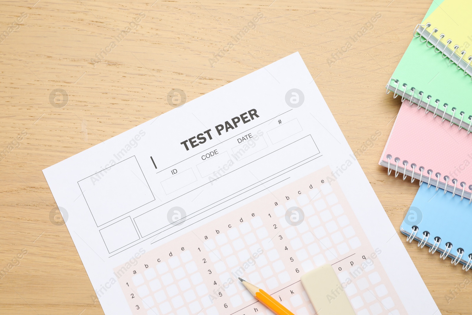 Answer sheet, eraser, pencil and notebooks on wooden table, flat lay. Student passing exam Photo of Answer sheet, eraser, pencil and notebooks on wooden table, flat lay. Student passing exam