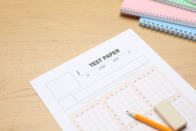 Photo of Answer sheet, eraser, pencil and notebooks on wooden table, closeup. Student passing exam